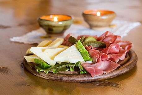 Rustic platter of alpine cheeses and cold cuts of Rinfreddo hut, Comelico, dolomites, Italy