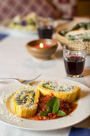 Roll of spinach and ricotta cheese with tomato sauce. Typical plate served in Malga Rinfreddo, Comelico, Dolomites, Italy