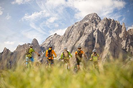 A young mountain bikers rest at Biscia summit, in the background the Sesto Dolomites, Cadore, Italy