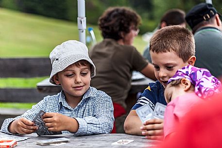 Children are playing cards at Pratopiazza hut, dolomites, Italy
