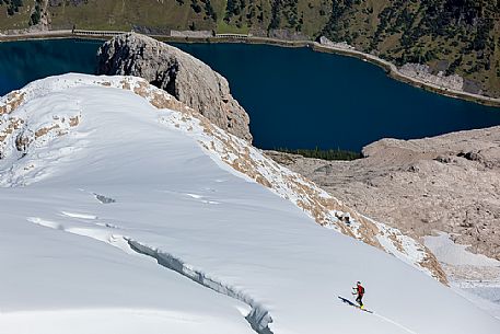 Ski mountaineering on the Marmolada glacier and in the background the Fedaia lake, dolomites, Belluno, Italy