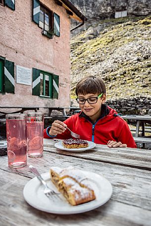 Young hiker eats a cake at Borletti hut, Venosta valley, Stelvio National Park, Italy