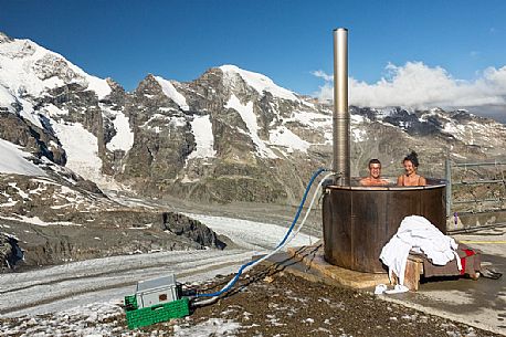 Tourists enjoing in the outdoor jacuzzi pool, in the background the Piz Bernina mountain range, Diavolezza Hut, Pontresina, Engadin, Canton of Grisons, Switzerland, Europe
 