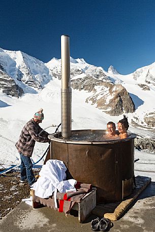 Tourists enjoing in the outdoor jacuzzi pool, in the background the Cresta Guzza, Bellavista and Piz Palu in the Bernina mountain range, Diavolezza Hut, Pontresina, Engadin, Canton of Grisons, Switzerland, Europe
 