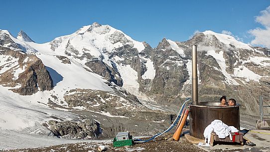 Tourists enjoing in the outdoor jacuzzi pool, in the background the Cresta Guzza and Piz Bernina peaks, Diavolezza Hut, Pontresina, Engadin, Canton of Grisons, Switzerland, Europe
 