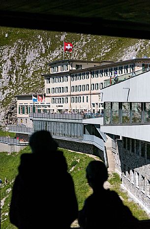 Tourists silhouette looking the Pilatus Klum hotel on Pilatus mountain from summit station of Cogwheel Railway , Lucerne, Border Area between the Cantons of Lucerne, Nidwalden and Obwalden, Switzerland, Europe