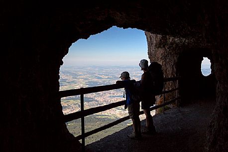 Hikers inside a rocky gallery on the Pilatus mountainn area, in the background the city and the lake of Lucerne, Border Area between the Cantons of Lucerne, Nidwalden and Obwalden, Switzerland, Europe