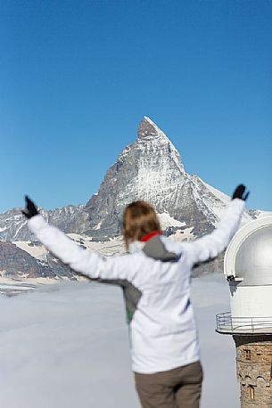 Woman in the top of Gornergrat admiring the Matterhorn or Cervino mountain peak and the astronomic observatory of Klum Hotel, Zermatt, Valis, Switzerland, Europe