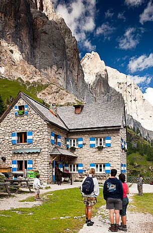 Hikers admiring the south big wall of Marmolada from the Rifugio Falier hut, Val Ombretta, dolomites, Veneto, Italy, Europe