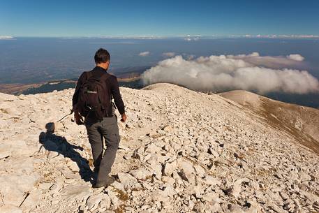 Hiker in the scree of Focalone mount in the Murelle amphitheater,in the background the Adriatic coast, Majella national park, Abruzzo, Italy, Europe