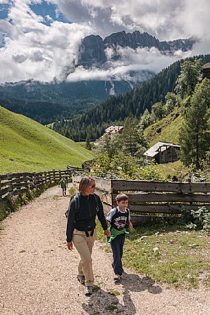 Mother and child walk in valle dei Mulini valley, in the background the dolomites of Puez, Badia valley, Trentino Alto Adige, Italy, Europe