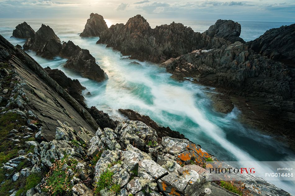 Oblique rocks raising from the water, making their stand at the ocean's strength