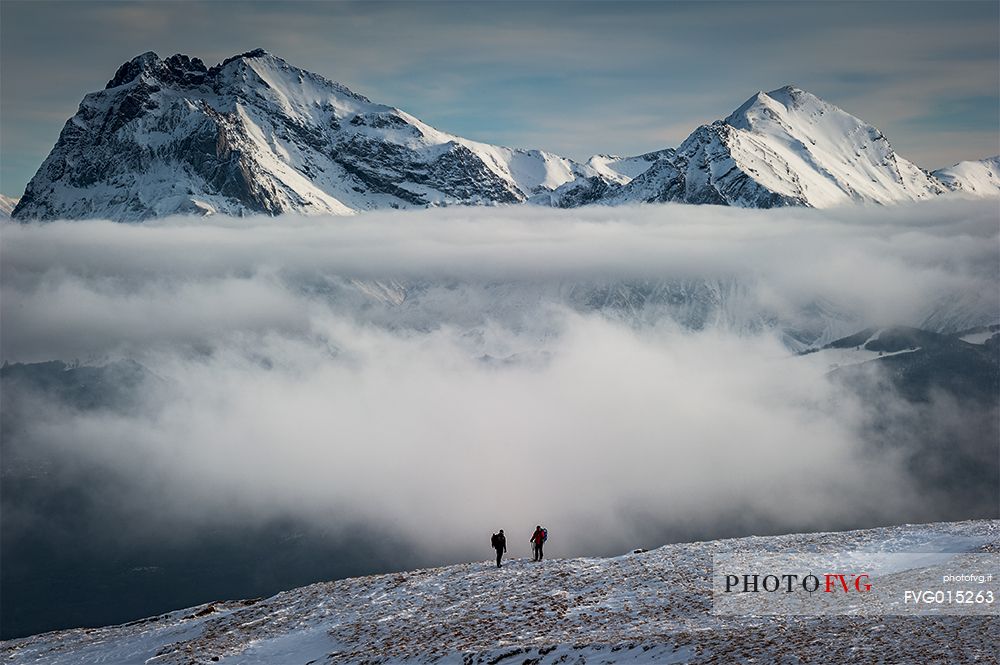 Symmetrical clouds between the two Gran Sasso Peaks, and two trekkers, Abruzzo, Italy, Europe 