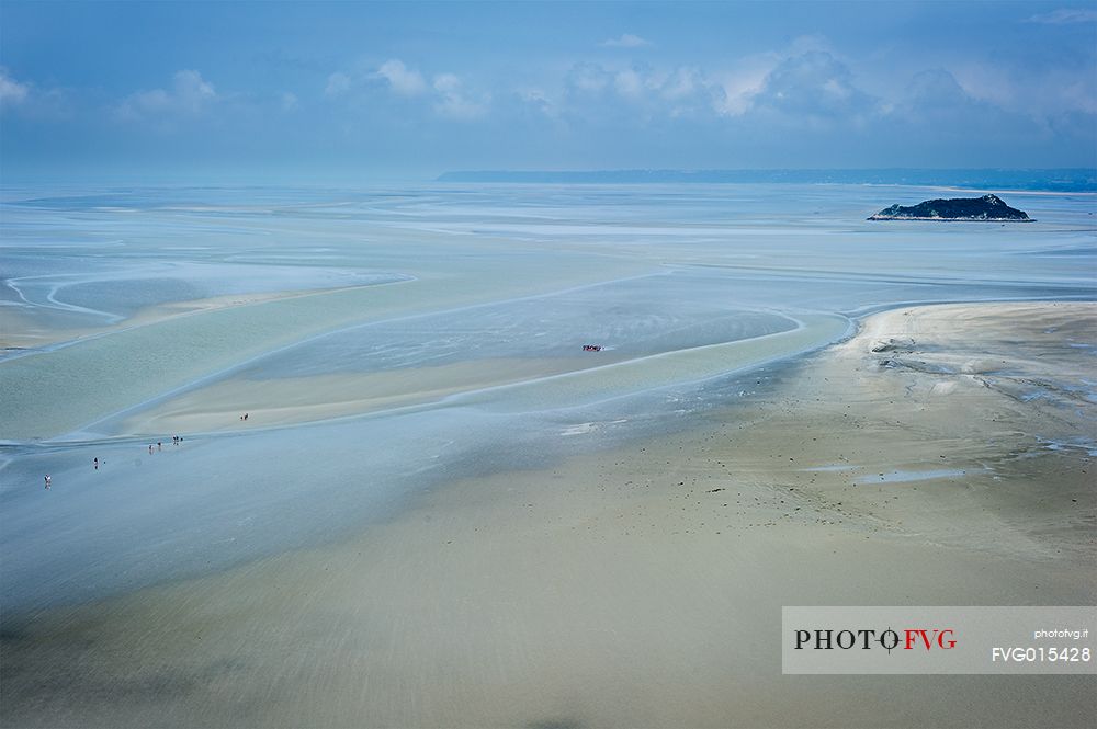 The shoal of Mont Saint Michel discovers the bottom of the sea, where tourists venture reaching the islets by foot .