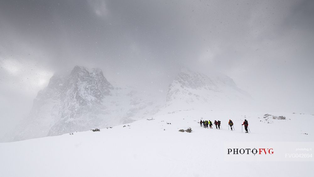 A group of hikers proceed towards the Gran Sasso during a snowstorm, Gran Sasso national park, Abruzzo, Italy, Europe
