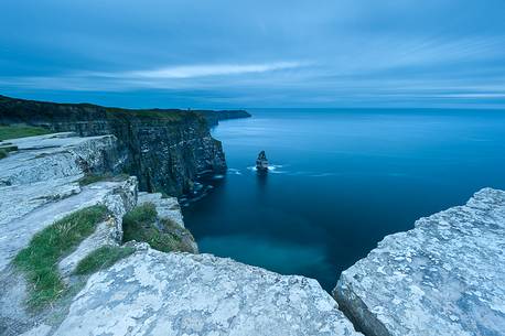 Rocks into the foreground along the Cliffs of Moher's path, during the blue hour