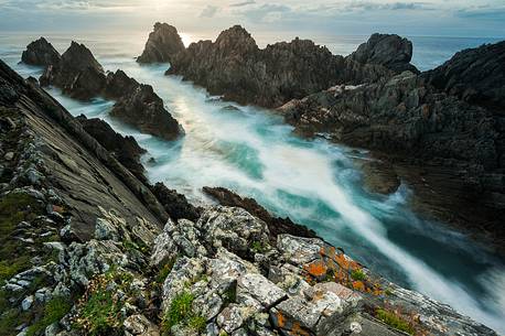 Oblique rocks raising from the water, making their stand at the ocean's strength