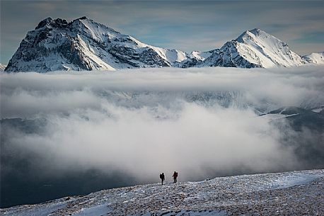 Symmetrical clouds between the two Gran Sasso Peaks, and two trekkers, Abruzzo, Italy, Europe