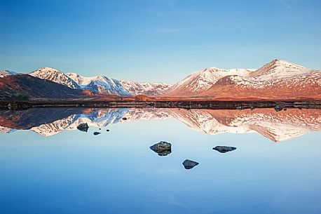 Only the stones emerging from the waters of Loch Nah-Achlaise reveal the presence of the water itself in this perfect reflection at sunrise.