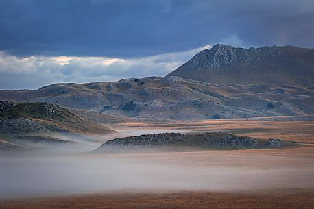 The plain of Campo Imperatore and Monte Bolza in the background during a foggy twilight 