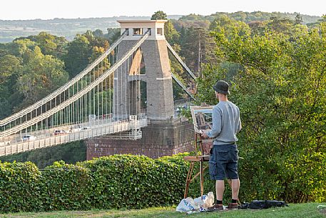 Young man paints a picture of the Bristol's Clifton Suspension Bridge, a distinctive landmark in Bristol, England, UK