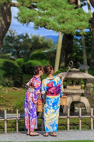 Two girls in kimono take a selfie in the Kenroku-en garden in Kanazawa, Japan
