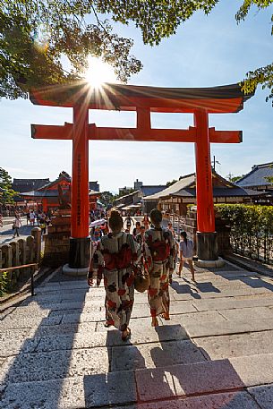 Asian women in traditional japanese kimonos at Romon Gate, shrine's entrance of the colored Fushimi Inari Taisha Shinto Temple, Kyoto, Japan