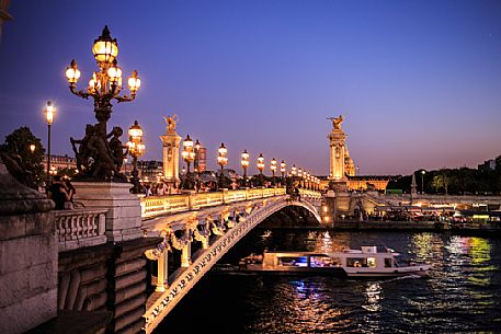 The Alexander III bridge at twilight while passing a Bateau Mouche, Paris, France, Europe