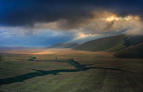 The first rays of sun illuminate the Pian Grande plain of Castelluccio di Norcia at dawn, Umbria, Italy, Europe