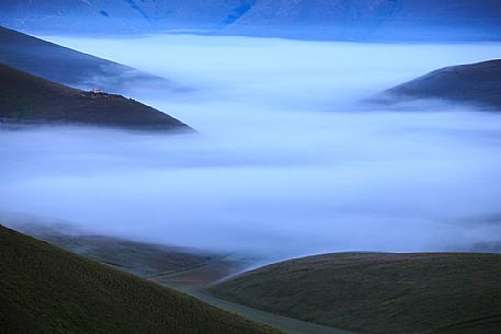 The Pian Piccolo covered by fog at the first light of the morning, Sibillini mountains, Castelluccio di Norcia, Umbria, Italy.