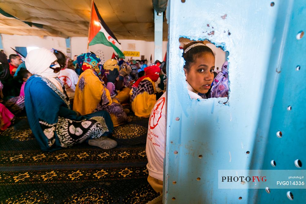 A young girl sitting on the floor during a meeting in the refugee camp of Dahkla