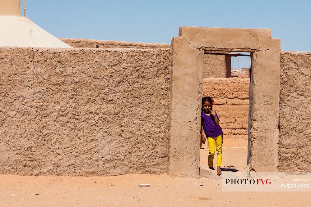 A young girl looking at the camera from the door of her 