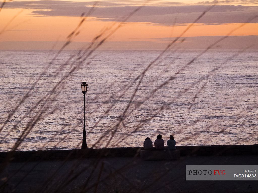 Three people admiring an amazing sunset in Muxa