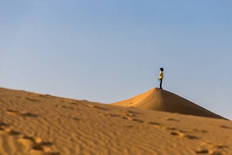 A young girl looking at the horizon from above a sand dune