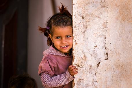 A child looking at the camera from the door of her classroom in a local school