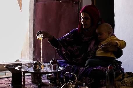 A Saharawi woman preparing tea for guests with her baby