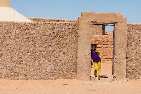 A young girl looking at the camera from the door of her A young girl looking at the camera from the door of her