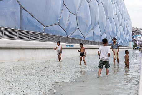 Children playing outside the Beijing National Aquatics Center (called Water Cube) inside the Olympic Green, the olympic park built for 2008 Summer Olympics, China