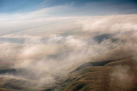 The fog on the plain alternates suggestive views in a slow decline, Castelluccio di Norcia, Sibillini National Park, Italy, Europe