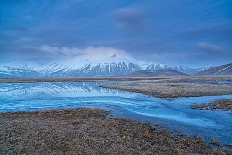 Snow melting in the Pian Grande of Castelluccio di Norcia at twilight, in the background the Vettore mountain, Sibillini National Park, Umbria, Italy, Europe