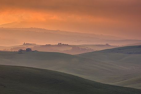 The beauty of the hills in Val d'Orcia at sunset, ridges and farmhouses typical of Tuscan beauties, Orcia valley, Tuscany, Italy