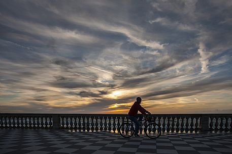 Cyclist rides on the Mascagni terrace at sunset, Livorno, Tuscany, Italy