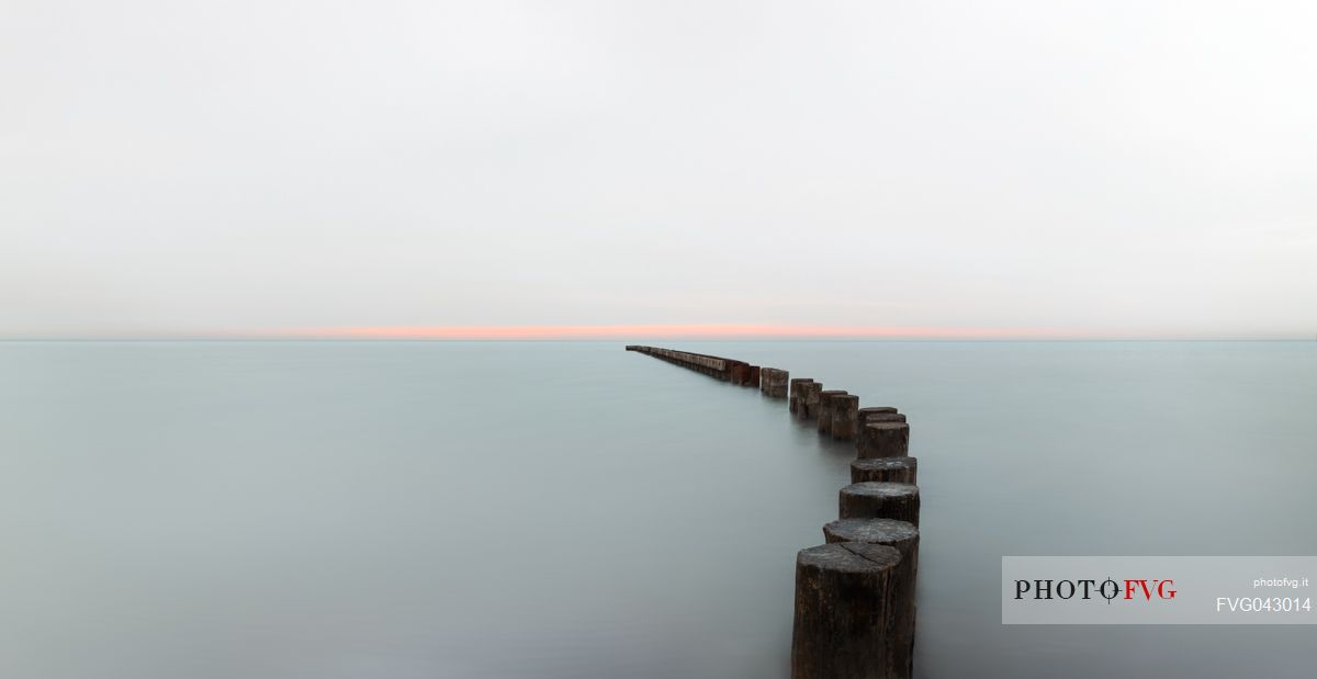 A wooden pile trail points towards the horizon between sky and sea, Bibione, Adriatic sea, Veneto, Italy, Europe
