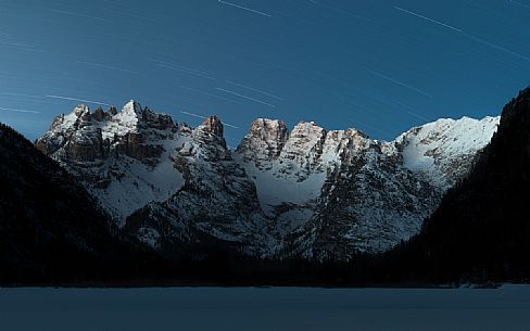First lights on Monte Cristallo mountain range during a winter dawn with stars in the sky, Landro lake, South Tyrol, dolomites, Italy, Europe