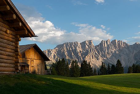 The  Latemar framed by a blu sky, a green meadow and a chalet made of wood, Carezza, dolomites, Trentino Alto Adige, Italy, Europe