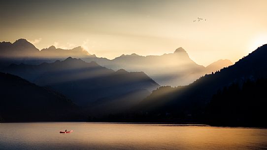 A canoeist crosses the Barcis lake at sunset, Dolomiti Friulane natural park, dolomites, Friuli Venezia Giulia, Italy, Europe