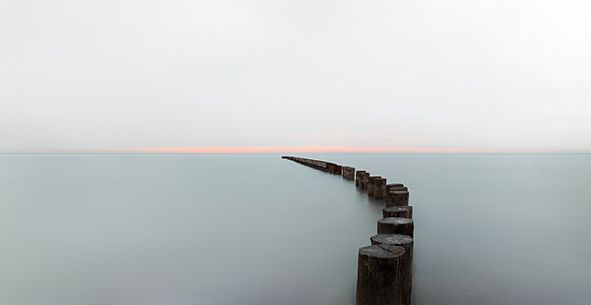 A wooden pile trail points towards the horizon between sky and sea, Bibione, Adriatic sea, Veneto, Italy, Europe