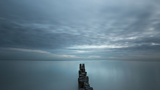 A wooden pile trail points towards the horizon between sky and sea, Bibione, Adriatic sea, Veneto, Italy, Europe