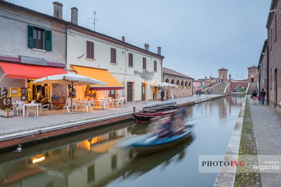Evening view of Tre Ponti bridge with a tipical fisherman ship and a food shop
