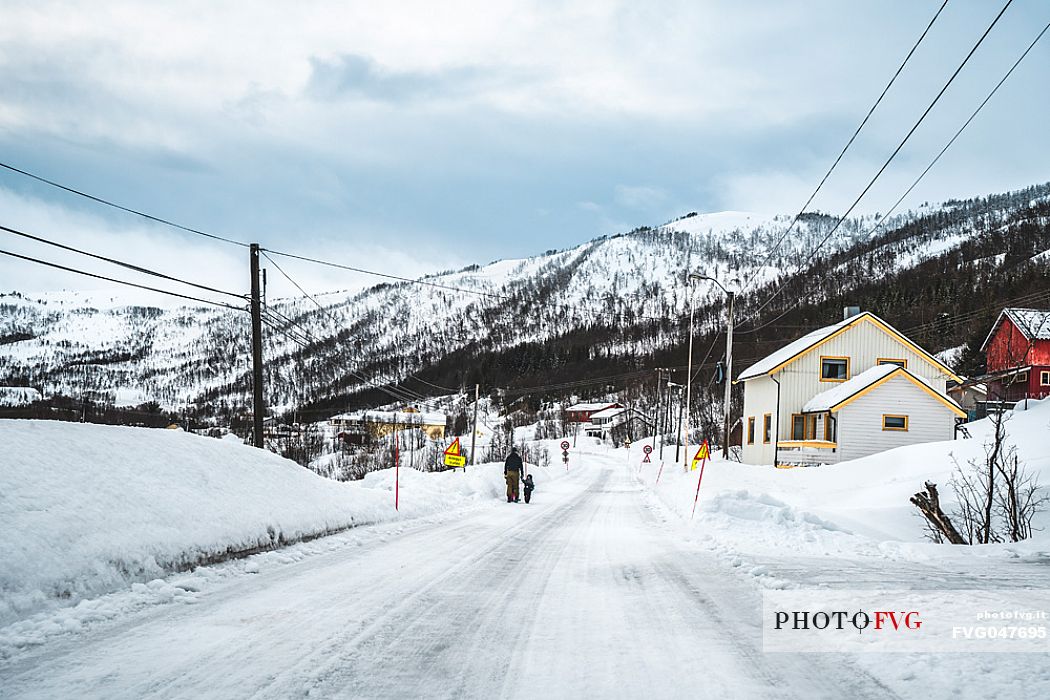 Father walks with his children on a norwegian icy road, view from road 862, near Tromso, Norway, Europe